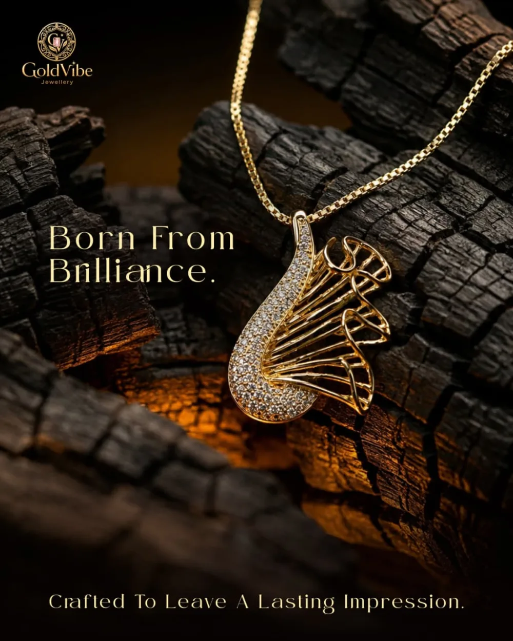 A stone-set GoldVibe pendant on a fine chain, resting on charcoal.